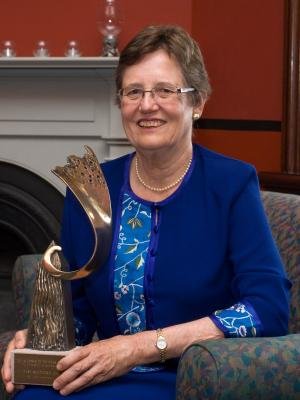 A woman in a blue dress holding a trophy